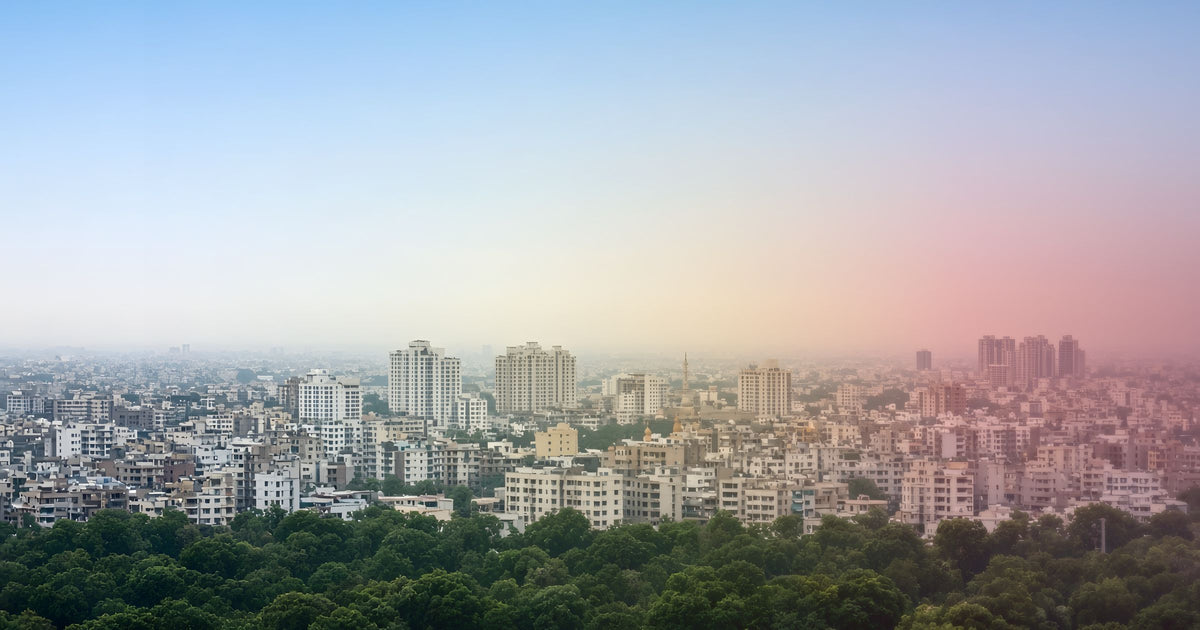 City skyline on a clear morning at left, fading into haze tinted in AQI colours from green to maroon at right