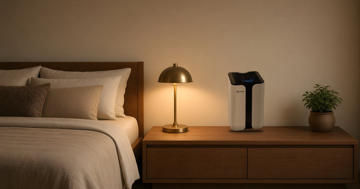 Airnest Core air purifier on a wooden bedside table next to a glowing lamp in a calm bedroom at night